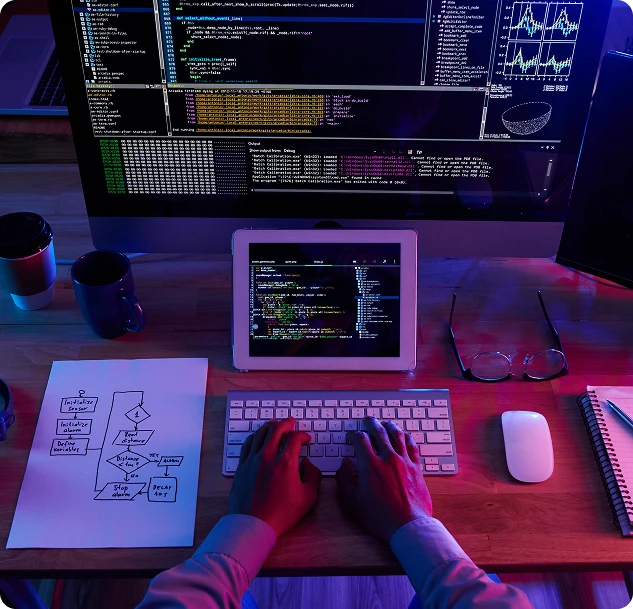 Full stack engineer coding at a multi-screen workstation with flowchart notes