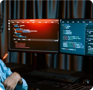 Developer working on backend code displayed across dual monitors in a dark environment