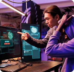 Cybersecurity engineer analyzing threat data on multiple screens with access denied alert