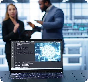 Two professionals discussing AI development project with neural network displayed on laptop